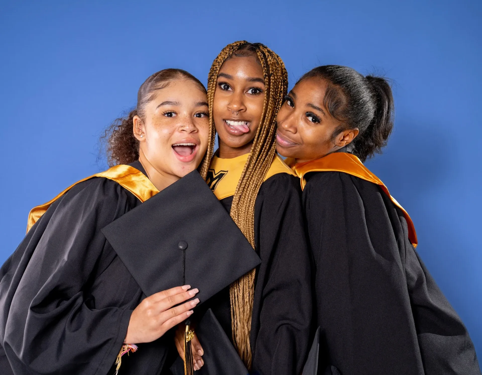 Three young women in graduation robes and caps.