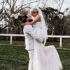 A bride and groom are hugging in the grass.