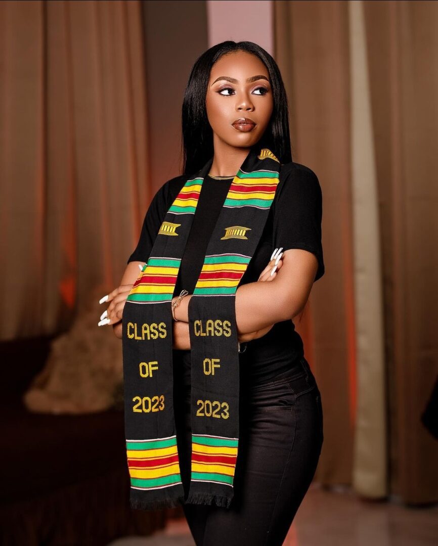 A woman wearing a black shirt and a rasta colored scarf.