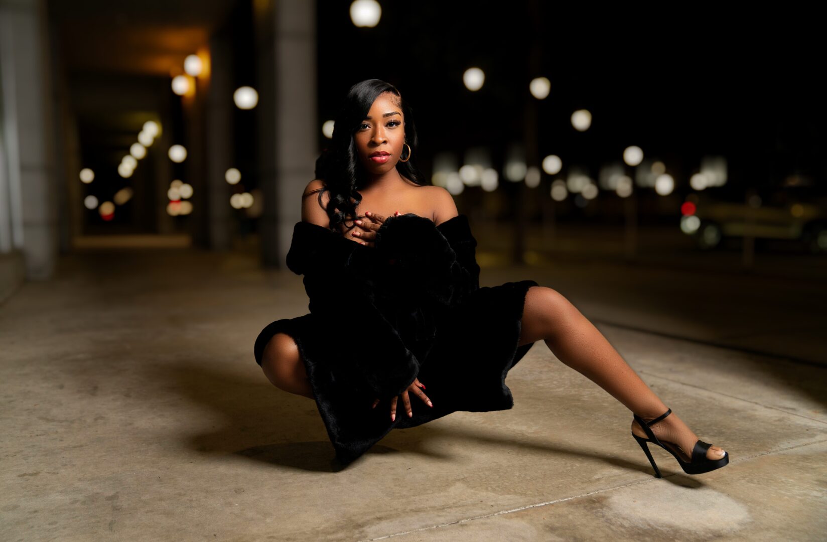 A woman in black dress sitting on the ground.